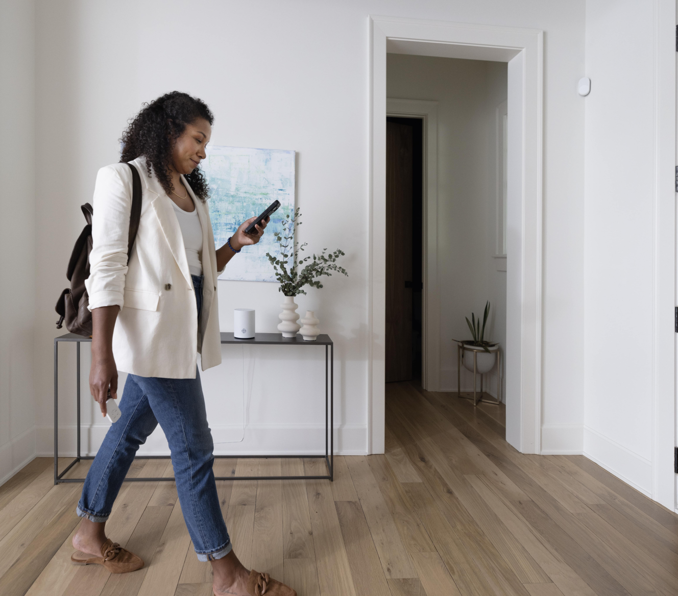 Women on her phone checking the ADT+ app with the ADT Base on a table