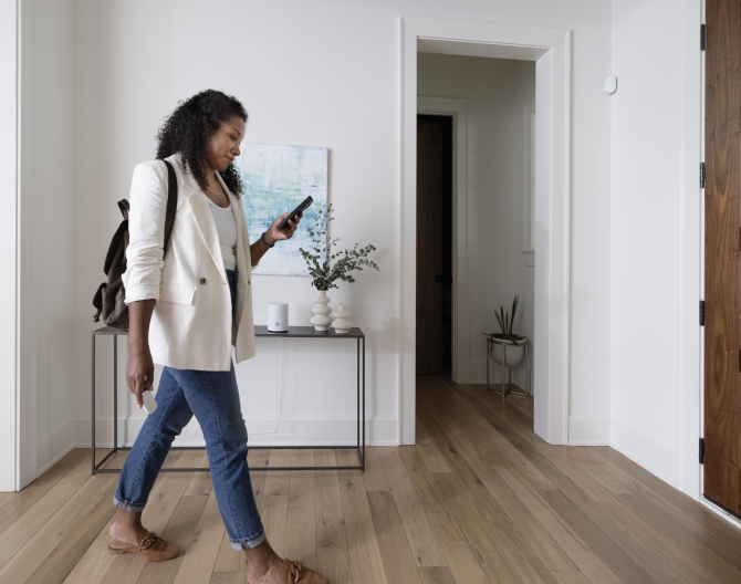 Women on her phone checking the ADT+ app with the ADT Base on a table