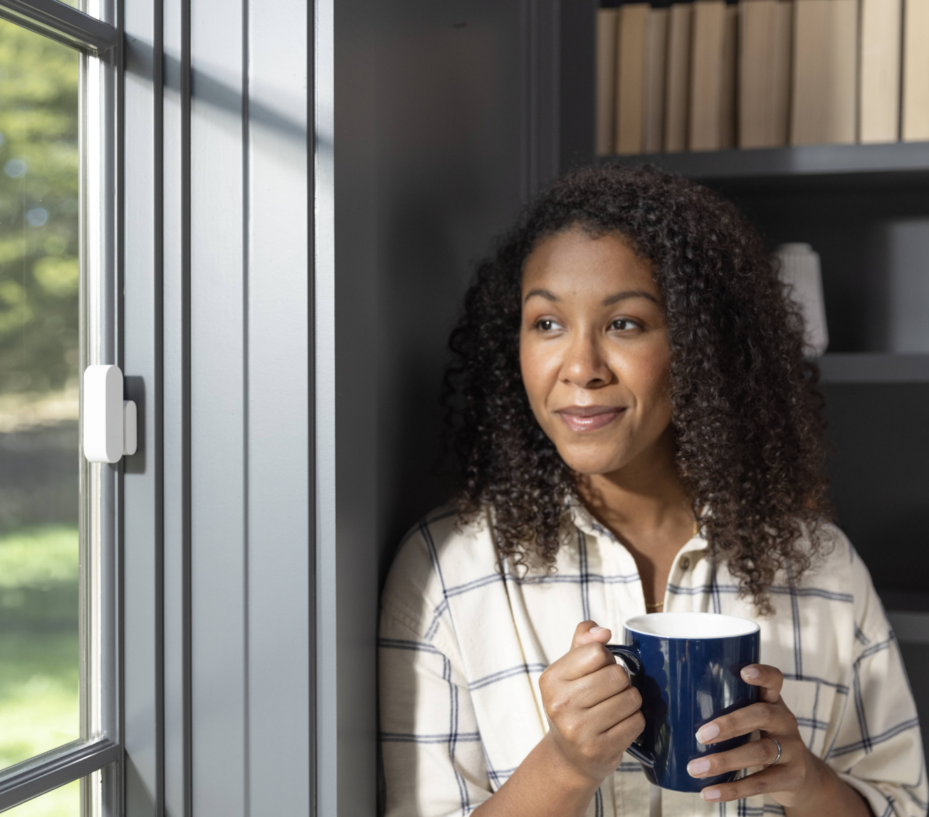 ADT customer standing next to her window that has a ADT Door/Window Sensor installed