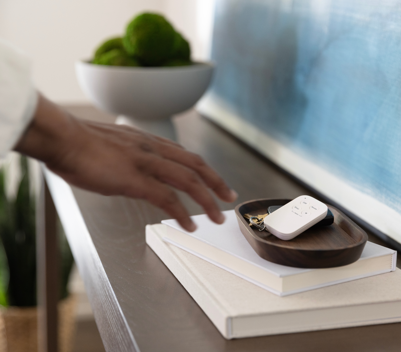 Hand reaching for the ADT Keychain Remote on a side table