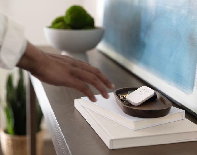 Hand reaching for the ADT Keychain Remote on a side table