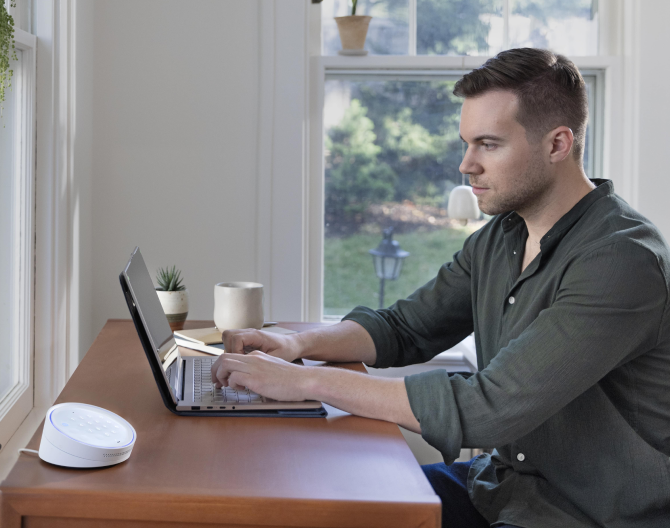 Man working on his laptop at a table with the ADT Keypad next to him