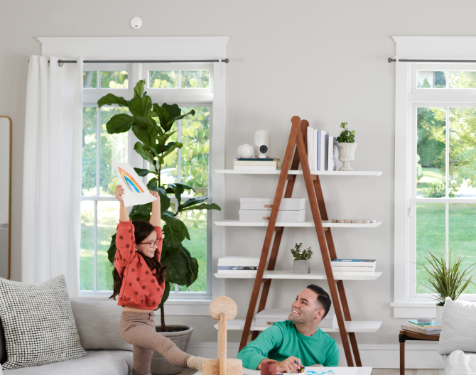 Family in the living room with an ADT Battery Smoke Detector on the wall