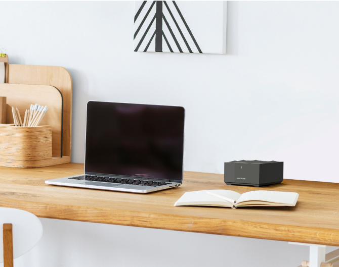 Netgear Mesh WiFi on a wooden desk next to a laptop and notebook