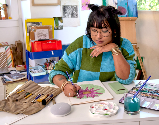 Women painting a picture next to a Google Nest Mini 2 Gen on a table