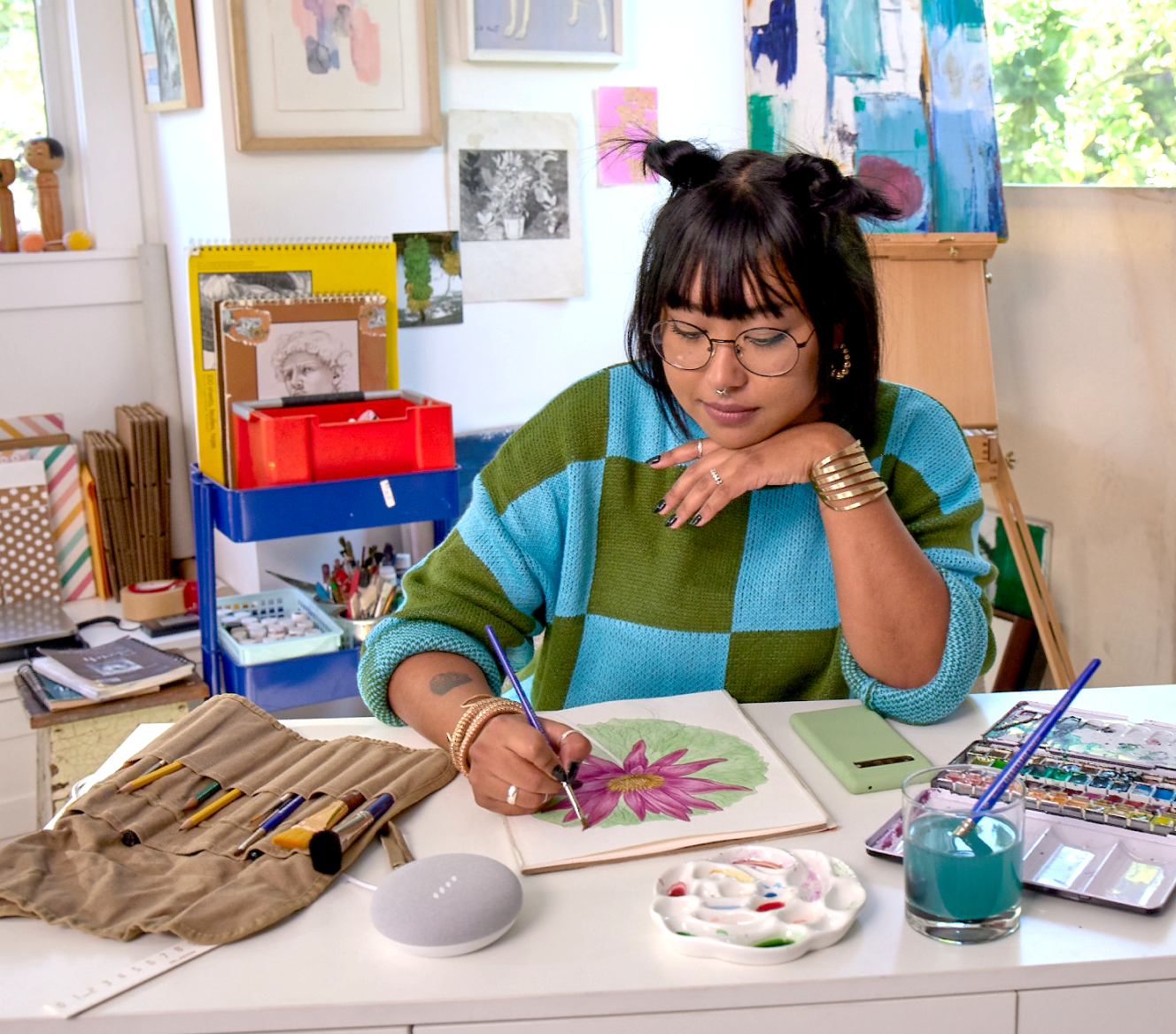 Women painting a picture next to a Google Nest Mini 2 Gen on a table